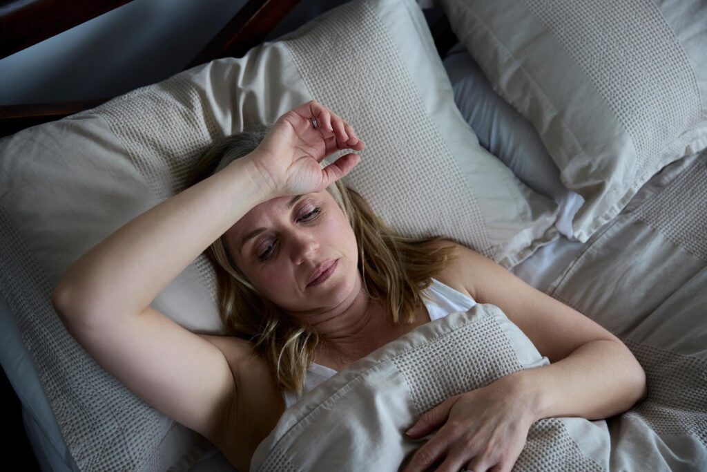Woman in bed and unable to sleep due to suffering from elbow pain at night